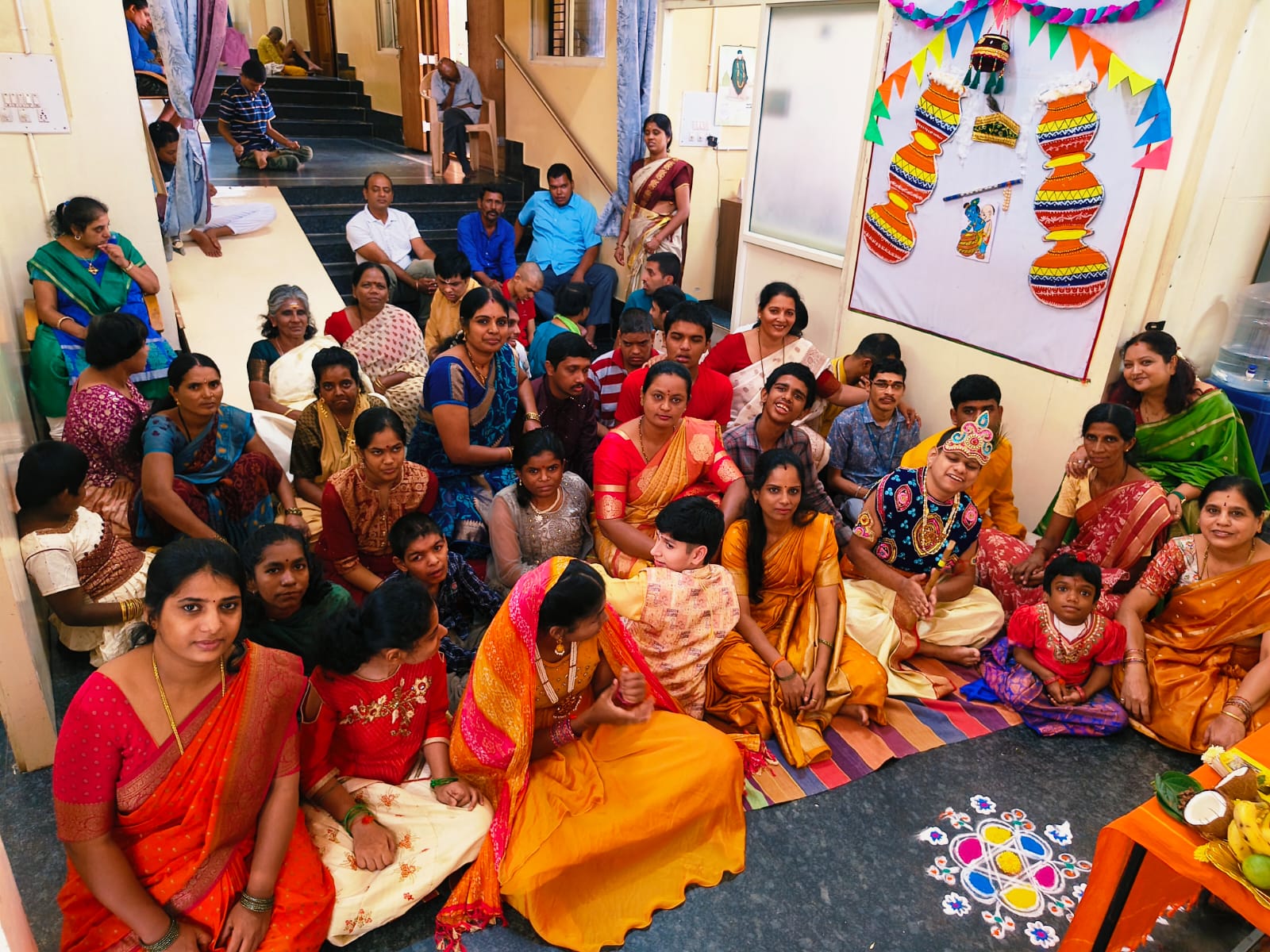 Children, families and staff gathered together for Krishna Janmashtami celebrations beside a decorated matki display